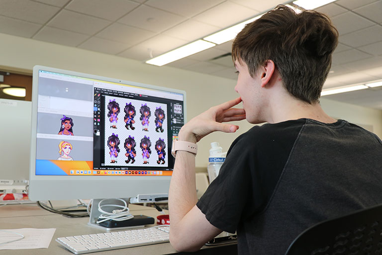 A student creates 2D characters on a computer.